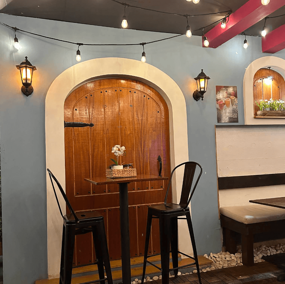High-top table by the arched wooden door and lantern sconces